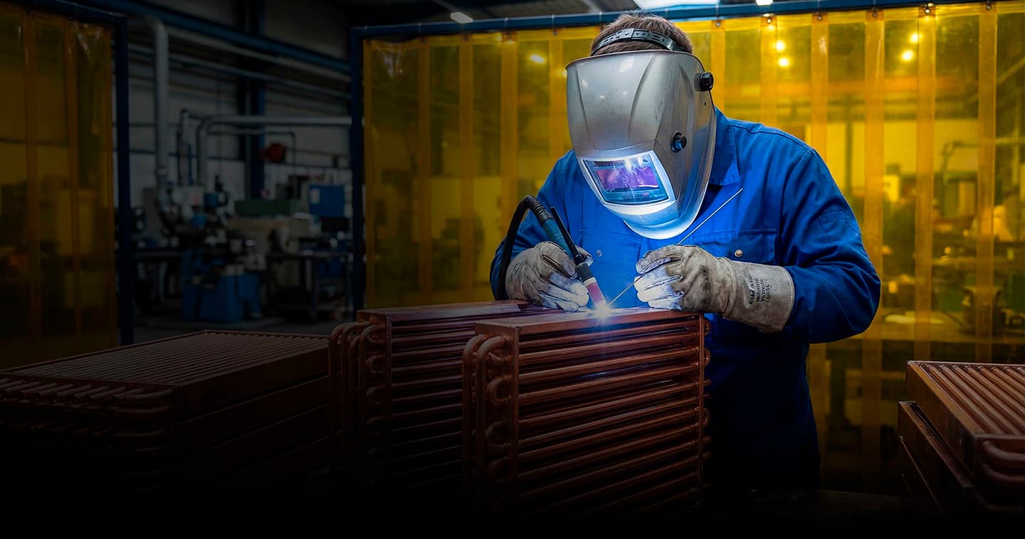 Soldador trabajando sobre un núcleo de radiador de cobre